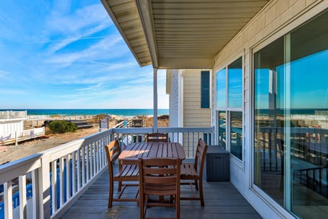 Beachfront property balcony with ocean views and outdoor dining setup for coastal relaxation.