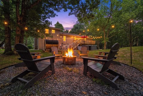 Everything you came for --- fire pit, private hot tub, barrel sauna, and a spacious deck, all glowing at twilight in your own Poconos backyard retreat.