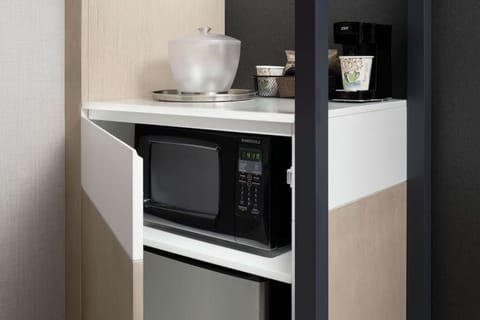 Microwave, mini-fridge, and coffee maker in corner shelf