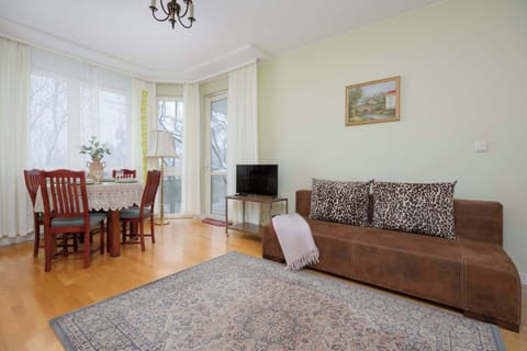 Bright bedroom featuring a fold-out sofa, wooden flooring, soft textiles, and natural daylight.