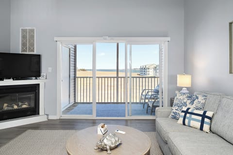 4306 Pettinaro Drive, Bethany Bay - Ocean View - Deck access - View of the corner fireplace and wall-mounted TV, featuring sliding glass doors that open to the waterfront balcony.