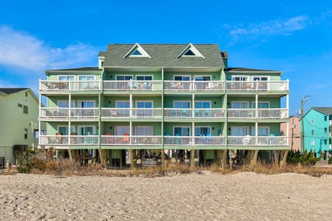 Beachfront property with multiple balconies offering direct beach access and colorful neighboring homes.