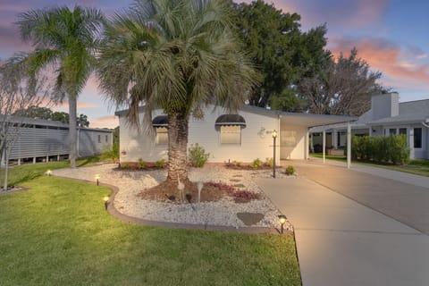 Tropical paradise awaits at this charming Florida home, featuring palm trees and landscaped gardens under stunning sunset skies.