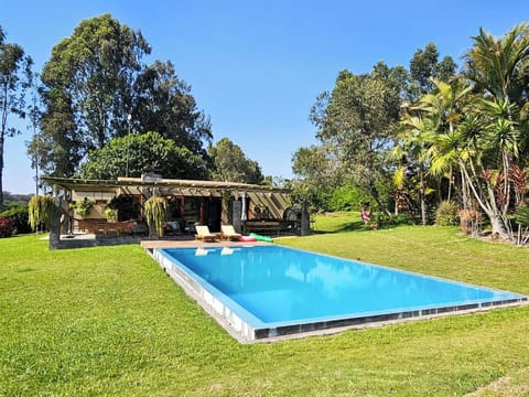 Spacious garden with a private swimming pool, surrounded by trees and open green areas—perfect for relaxing under the sun.