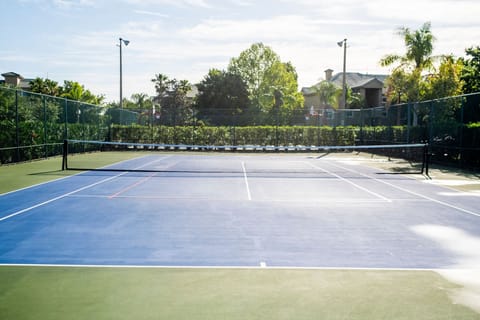 Enjoy a sunny day on this tennis court surrounded by lush landscaping.