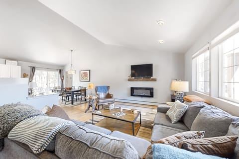 Spacious family room with a comfortable sectional sofa and smart TV. The space flows seamlessly into the large kitchen dining area.