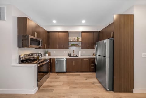 Your fully equipped kitchen features sleek modern appliances, ample counter space, and warm wood cabinetry for memorable meal preparation.
