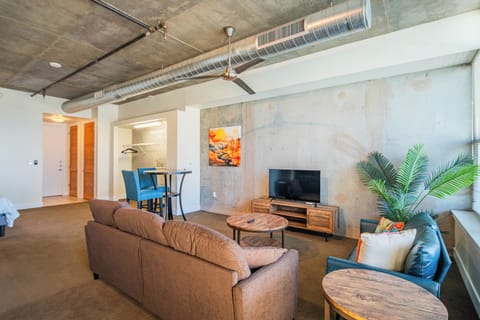 Relax in your modern living space with exposed concrete ceilings, cozy seating, and contemporary design touches that create an industrial-chic atmosphere.