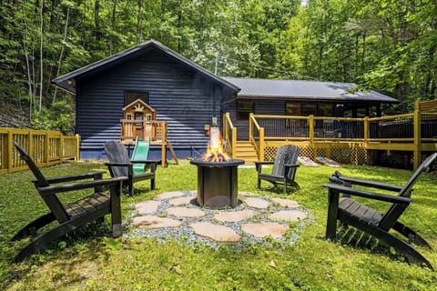 A charming forest retreat with a cozy fire pit surrounded by Adirondack chairs, perfect for evening gatherings under the trees. The spacious deck and playhouse add fun for all ages.