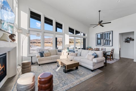 A bright and light filled primary living room / great room with cozy fireplace, views for days and a wonderful deck overlooking the 11th green and fairway of the Golfpark