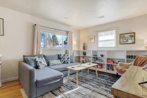 Sunlit lounge with a gray sectional, patterned rug, and a wood coffee table—kick back with a book from the built-in shelves while daylight pours in through the windows.