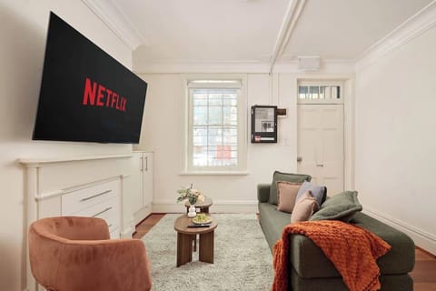 Living Room :
Inviting living room with sage green sofa, coral velvet accent chairs, and large Smart TV. Heritage ceiling details, polished timber floors, and cozy styling create the perfect space to relax and unwind.