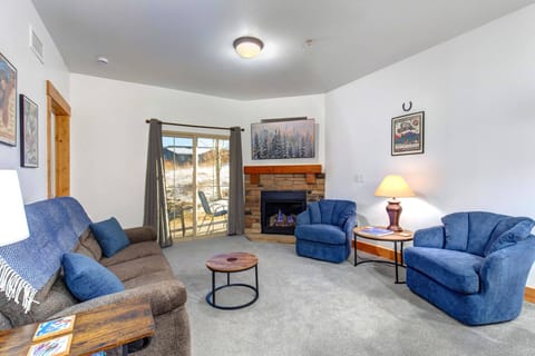 Sink into plush blue chairs by your crackling stone fireplace, where mountain views through sliding doors create the perfect backdrop for cozy evenings.