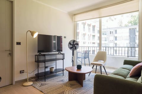 Bright and modern living room with a cozy sofa, large TV, and access to a private balcony with outdoor seating.