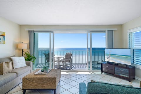 The coastal-inspired living space features comfortable seating, flat-screen TV, and floor-to-ceiling sliding doors to the beach balcony.