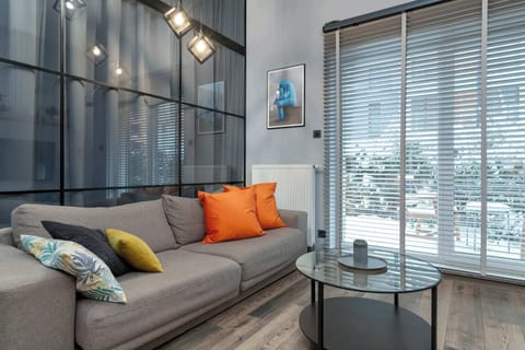 A contemporary living room with a sofa, round glass coffee table, and floor-to-ceiling windows. The space offers a relaxing atmosphere and plenty of daylight.