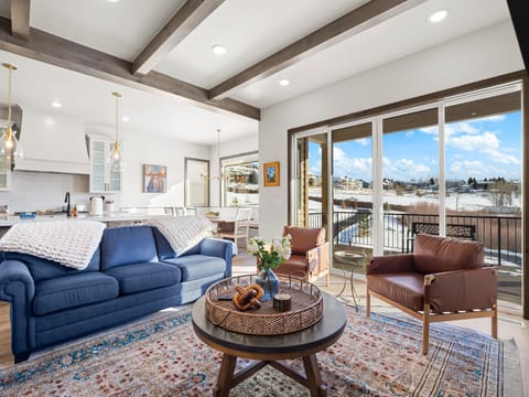 Primary living room at Summit View Lodge with large cozy gas fireplace, large smart TV, ample luxurious seating and a large amazing deck with unobstructed views of Mount Timpanogos