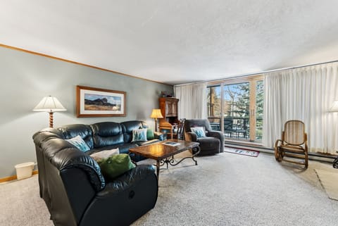 Sink into plush leather seating in your spacious living room, where large windows frame mountain views and natural light fills the space.