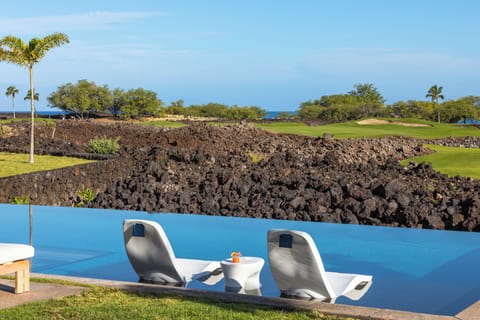 Stunning infinity pool overlooks volcanic landscape and championship golf course on Hawaii's pristine coastline.