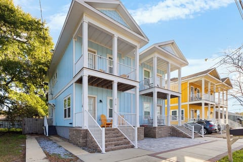 Charming coastal-style duplex featuring covered porches, modern architecture, and convenient neighborhood location with mature trees and parking.