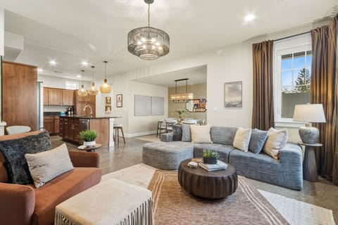 Unwind in your elegant living space where modern comfort meets sophisticated design, featuring plush seating and a stunning chandelier overhead.