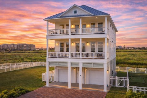 Elevated coastal beach house with covered parking, private driveway, and multiple balconies overlooking the Gulf Coast.