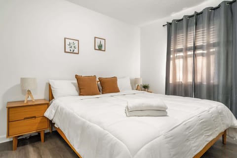 Bedroom 1: A comfortable bed, natural light streaming through large windows.