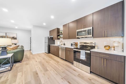 You'll love preparing meals in this sleek modern kitchen featuring stainless steel appliances, rich wood cabinetry, and warm hardwood floors.