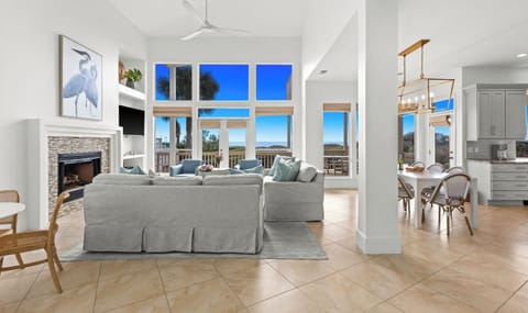 Relax in your bright, coastal living space where ocean views stretch beyond floor-to-ceiling windows and a cozy fireplace awaits evening moments.