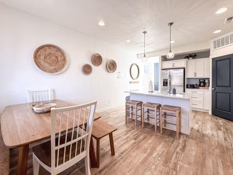 Bright modern kitchen-dining space with coastal touches, island seating, wood floors, perfect for relaxing stays.