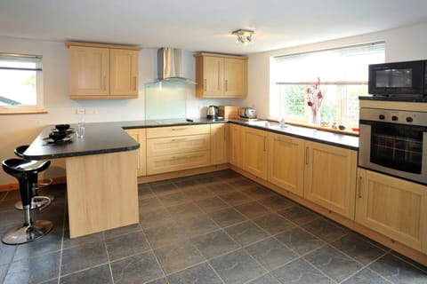 Kitchen with built-in oven, hob, microwave, kettle, toaster and two bar stools