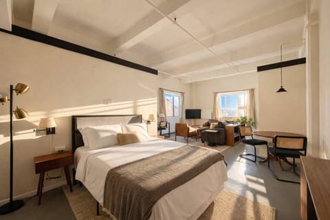 Welcome to your sun-drenched corner studio, featuring a plush queen bed and wall-to-wall windows