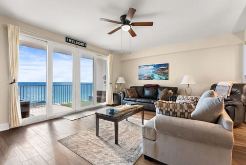 Cozy living room offers plush seating and stunning floor-to-ceiling Gulf views through oversized balcony doors