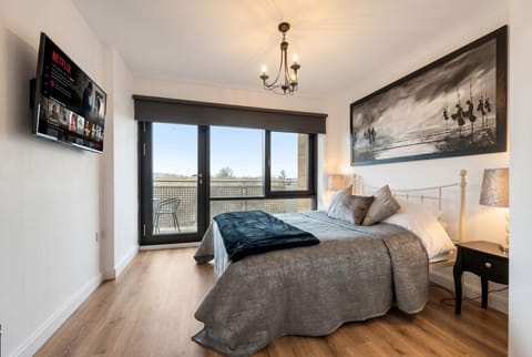 Wake to green views in this bright bedroom with Netflix TV and balcony doors.