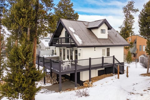 Mountain retreat surrounded by snow-dusted evergreens, featuring a spacious deck perfect for winter getaways.