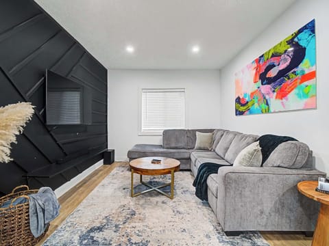 Bright living room w/ plush seating, colorful art & a sleek fireplace wall