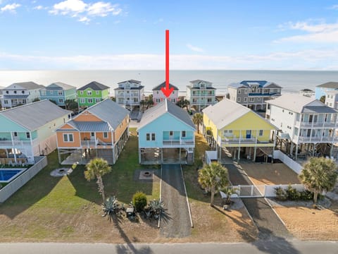 Aerial view of the home just steps from the beach. Elevated houses line quiet streets with ocean views, capturing the charm and relaxed lifestyle of a vibrant seaside community.
