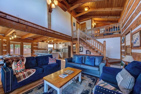Gather in your spacious open-concept living room, where rich wood beams and cozy blue seating create the perfect mountain retreat atmosphere.