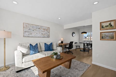 Sunlit living room with plush seating, stylish accents, and an open layout that flows into the dining and workspace—ideal for relaxing or working comfortably.