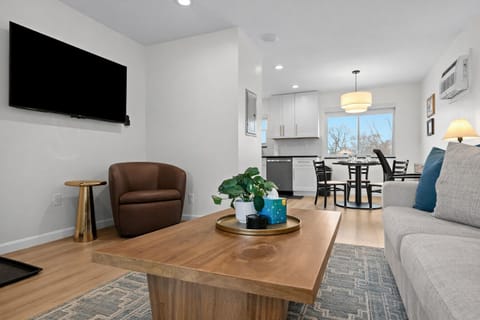 Spacious open-concept living area with cozy seating, smart TV, and seamless flow into the kitchen and dining spaceâperfect for relaxing or entertaining.