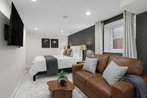 Stylish studio retreat featuring a plush bed, cozy leather seating, soft lighting, and smart TV—thoughtfully designed for comfort and a relaxing stay.