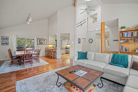 Relax in your open-concept living space with soaring ceilings, polished floors, and thoughtful touches like books and cozy throws.