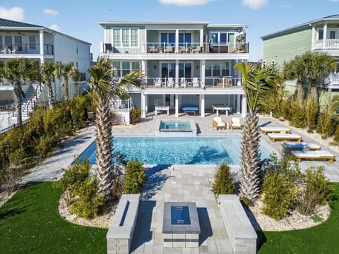 Resort-style rear exterior with expansive pool, water views, and outdoor living