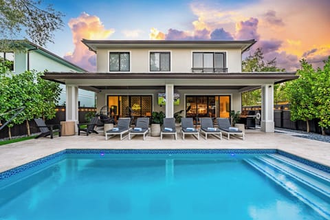 Outdoor patio with 75" Smart TV for streaming games or your favorite movie. Firepit, Adirondack chairs, golf putting green, hammock, string lights, BBQ grill, outdoor dining table for twelve, heated salt water pool, and outdoor shower.