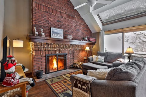 The living room has a large sectional sofa, a smart TV, and a wood-burning fireplace.