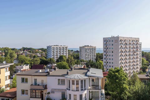 A view of the city from above, capturing multiple residential buildings. The scene highlights the apartment’s elevated position and urban surroundings.