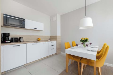 A compact kitchen and dining corner with white cabinetry, integrated appliances, and a small table set for two.