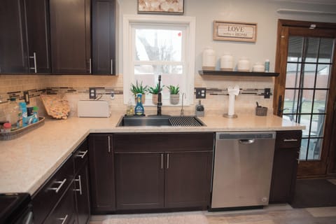 Bright, clean sink area with modern dishwasher and a charming window view.