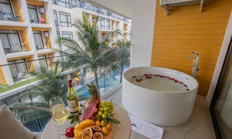 Outdoor bathtub on the balcony overlooking lush resort surroundings.