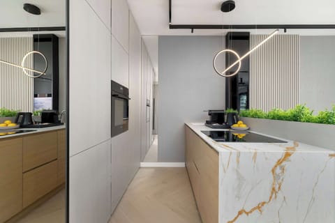 A sleek kitchen view focusing on the island and built-in appliances. Clean lines and neutral colors dominate the space. Subtle greenery adds a fresh accent.